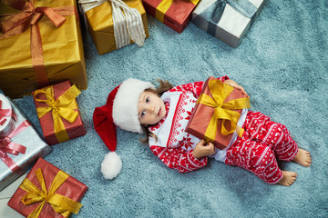 Happy little girl lies with a gift in her hands, top view, Christmas.