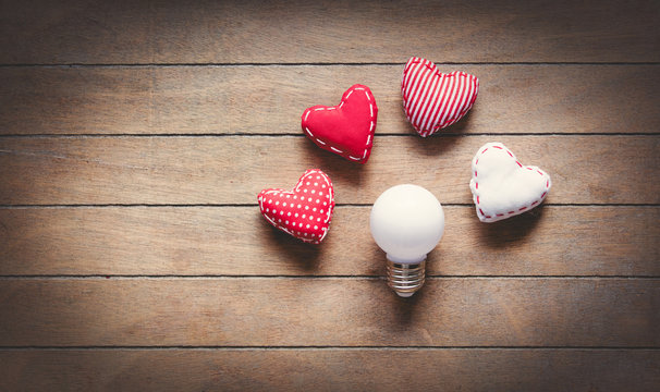 Heart shape toys and bulbs on wooden background