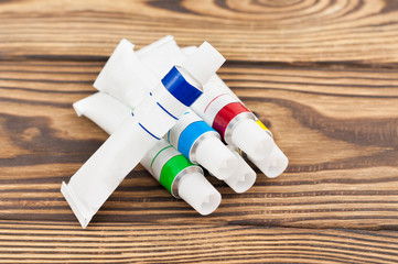 Heap of closed metal tubes of colored acrylic paint on old worn rustic table