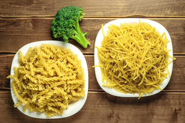Dry pasta on a plate on a wooden background. A white plate. A series of snapshots of healthy nutrition.
