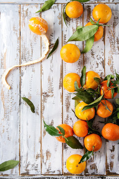 Ripe organic clementines or tangerines with leaves over white wooden plank table as background. Top view, space. Healthy eating