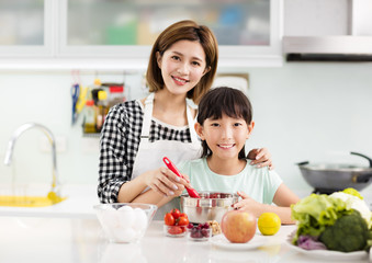 Obraz na płótnie Canvas Happy mother and child in kitchen preparing cookies.