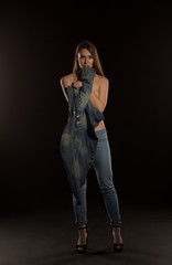 Gorgeous brunette woman in trendy jeans jacket posing at black background