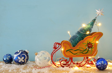 Image of christmas tree on the wooden old sled over snowy wooden table.
