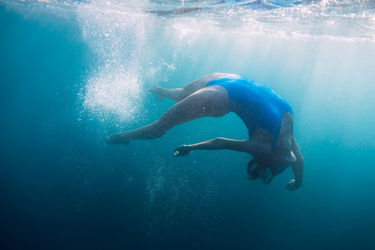 Woman swimming underwater in blue ocean, lifestyle