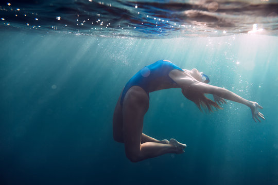 Sporty woman floating in sea, underwater in blue ocean