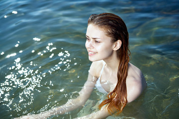 Young beautiful woman is swimming in the sea, white swimsuit, summer, water