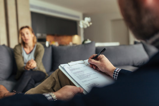 Psychologist writing notes during a therapy session with patient