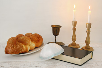 shabbat image. challah bread, shabbat wine and candles on the table.