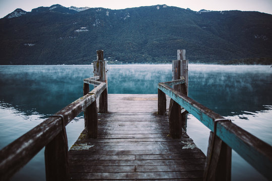 Empty wooden pier over river against mountain