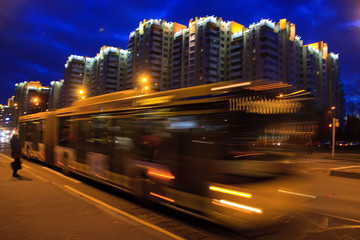 The motion of a blurred bus on the avenue in the evening