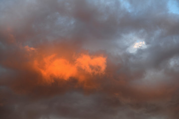 夕日を受けてオレンジ色に輝く雲と雲間に見える青空「空想・雲のモンスターたち（珍しいオレンジ色のモンスターなどのイメージ））」（オレンジ色に輝く、輝く人生、炎のパワー、不死身、情熱、熱情などのイメージ）