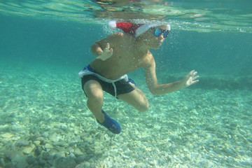 Boy in Santa hat swimming in sea