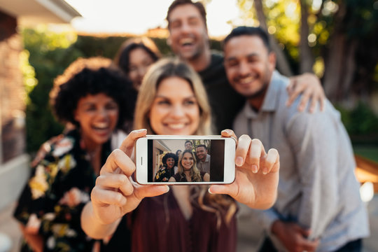 Joyful friends taking selfie during outdoor party