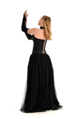 Naklejka premium full length portrait of a blonde girl wearing black gothic gown. standing pose, isolated on white background.
