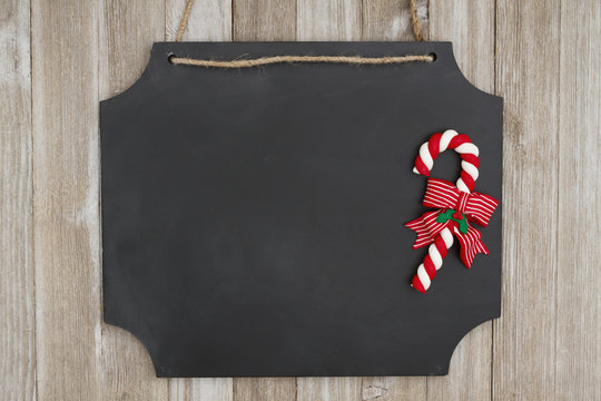 Hanging chalkboard with a candy cane on weathered wood wall