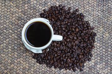 Coffee beans with white coffee mug blur background, A cup of hot coffee is placed beside the coffee beans