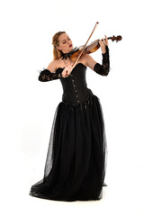 full length portrait of a blonde girl wearing black gothic gown. standing pose, isolated on white background.