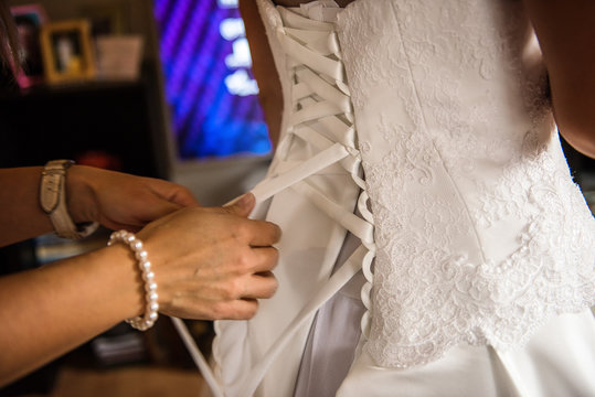 bridesmaid helping doing up corset dress