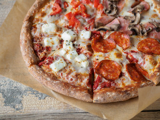 Homemade pizza set on paper at wooden table