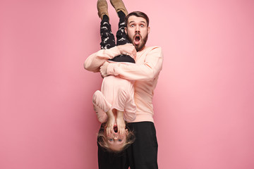 cheerful father playing with daughter on pink