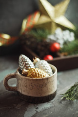 Christmas composition with cones in a cup and New Year decor on a dark background