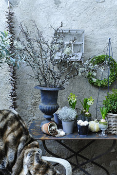 Terrasse et ambiance hivernale avec chaise en osier recouverte de plaid en fourrure, branches s&eacute;ch&eacute;es et arrangement d'hiver