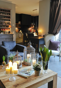 Salon cosy avec fauteuil bleu gris et table en bois et cuisine noire dans une atmosph&egrave;re hivernale 