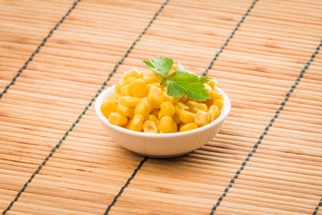 cooked sweet corn seeds in a  bowl on a wooden table. canned corn