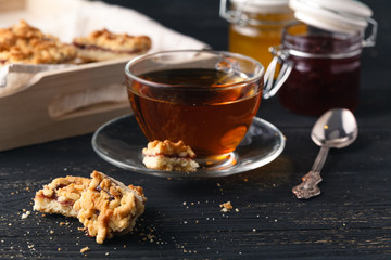 cup of tea and basket with cookies served for breakfast on wooden table, dark background
