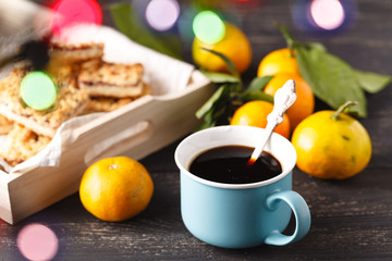 Cup of tea and branch with Christmas lights on background.