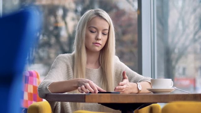 A blonde girl gets sad after looking at her smartphone.  