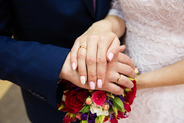 Bride and groom hands with wedding rings and beautiful bridal bouquet
