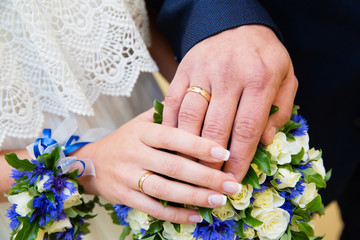 Bride and groom hands with wedding rings and beautiful bridal bouquet