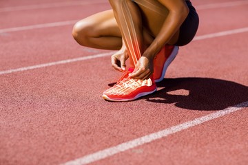 Female athlete tying shoelace on track