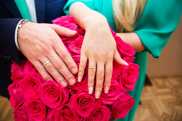 Obraz na płótnie Canvas Bride and groom hands with wedding rings and beautiful bridal bouquet
