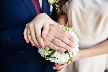 Bride and groom hands with wedding rings and beautiful bridal bouquet