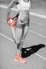 Low section of sportswoman stretching leg on sports track