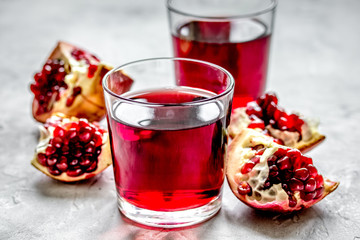 glass of pomegranate juice with fresh slices on stone background