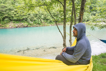 Man sitting in hammock - nature scene, water, silence