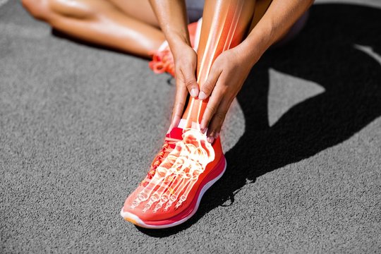 Low section of female athlete suffering from joint pain on track