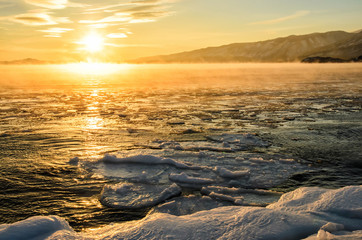 Ice floes floating on the fog water in the lake Baikal. Sunset