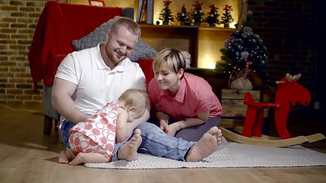 family, parenthood and people concept - happy mother and father playing with baby at home