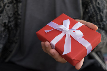 Christmas Present, Christmas Gift box closeup. Woman holding small red gift box with white ribbon