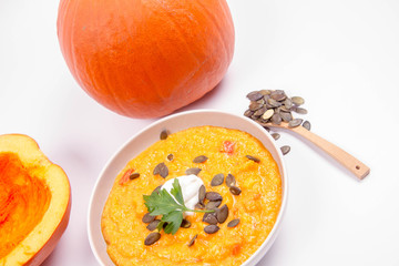 Pumpkin soup and pumpkins, pumpkin seeds, ginger and garlic on a white background