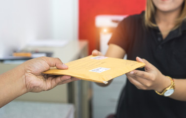 male hand send mail envelope to the female of post office before sending - obrazy, fototapety, plakaty