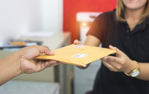 male hand send mail envelope to the female of post office before sending