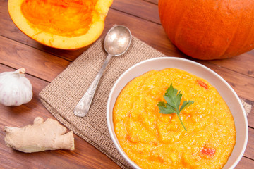 Fototapeta na wymiar Pumpkin soup and pumpkin, ginger and garlic on a wooden background