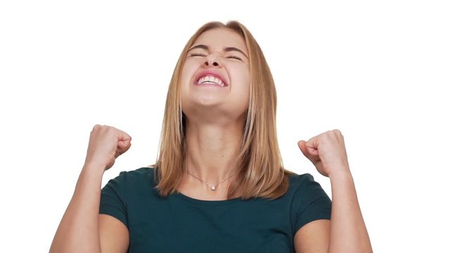 Headshot in slow motion of delighted woman being ecstatic about great news clenching fists in pleasure acting like winner or successful person over white background. Concept of emotions
