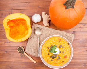 Pumpkin soup and pumpkins, pumpkin seeds, ginger and garlic on a wooden background